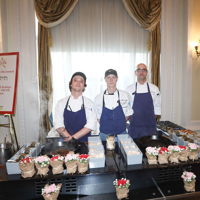 3 chefs stand behind a food station©2023804.363.7844 4976