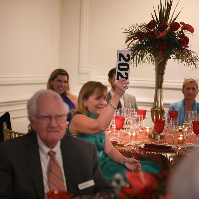 auction paddles are raised during a seated dinner