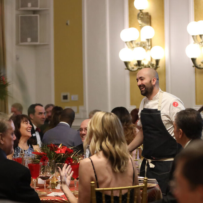 a chef greets guests at a seated dinner