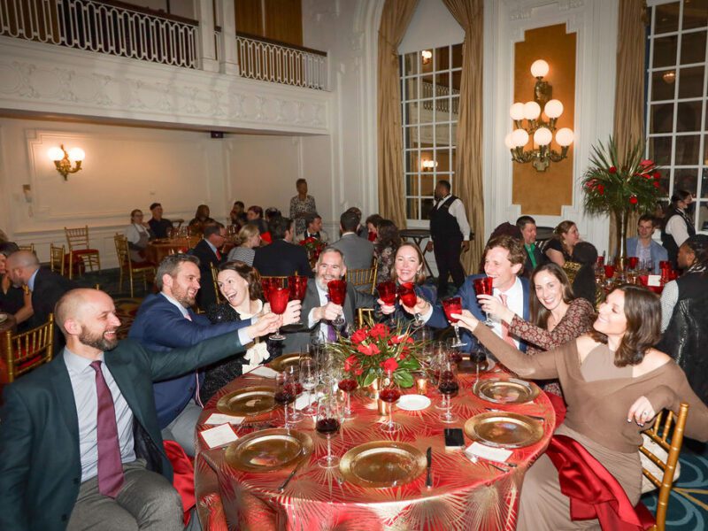 several adults toast with red glasses