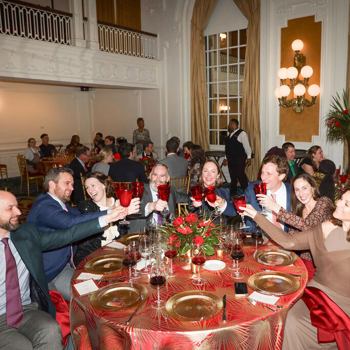 several adults toast with red glasses