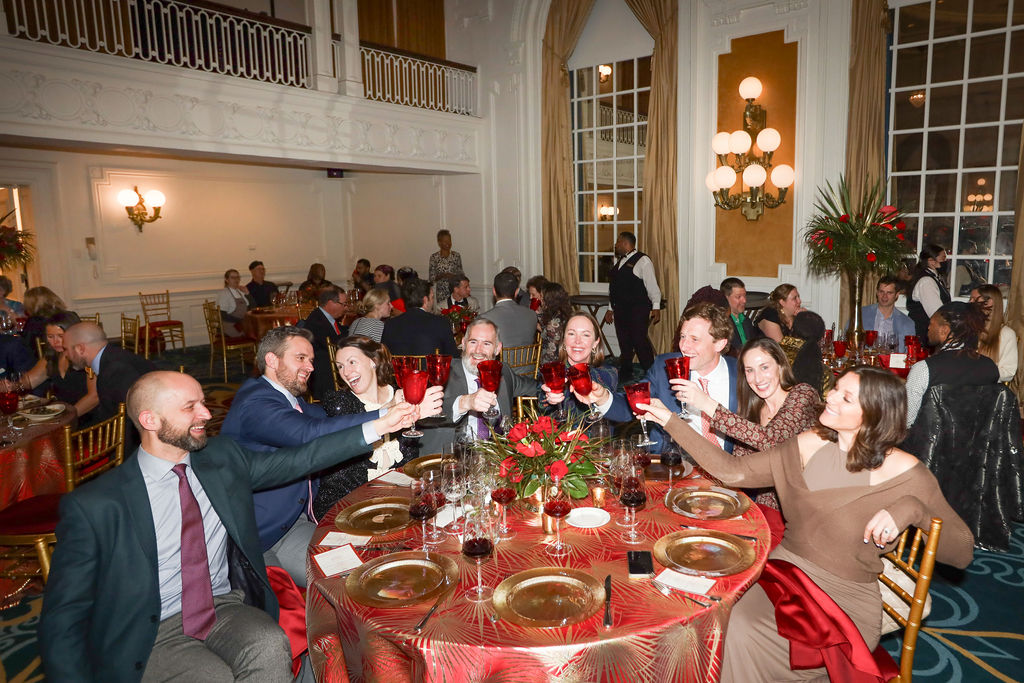 several adults toast with red glasses