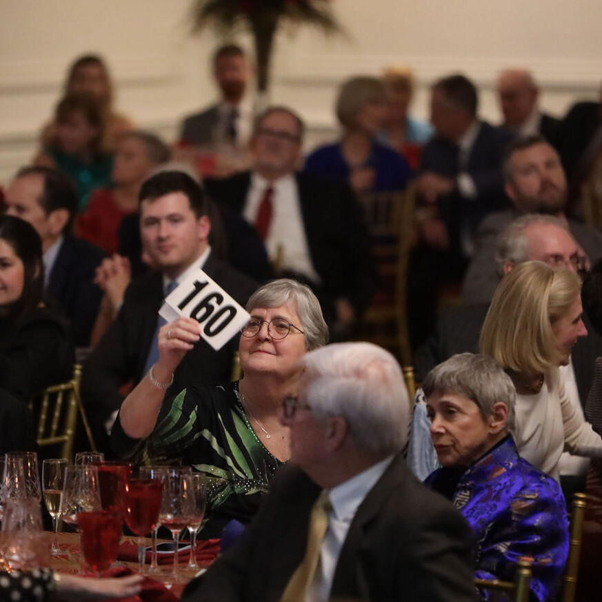 auction paddles are raised during a seated dinner
