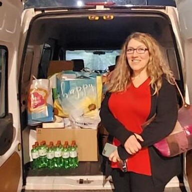 An adult poses with a large donation in an open car