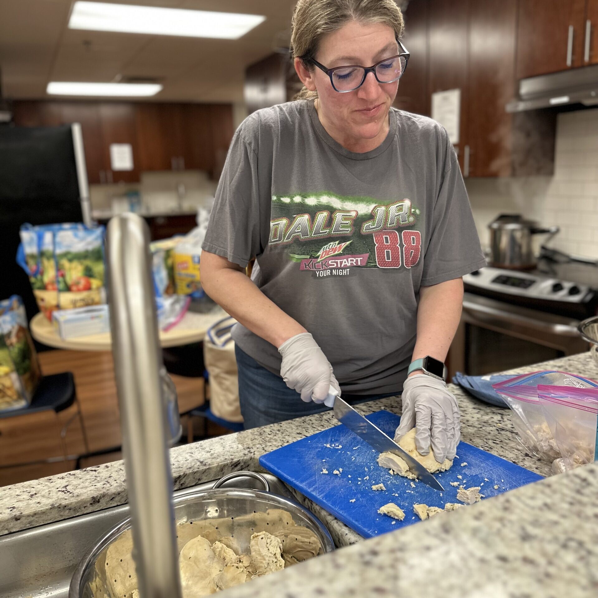A focused volunteer chops chicken on a cutting board