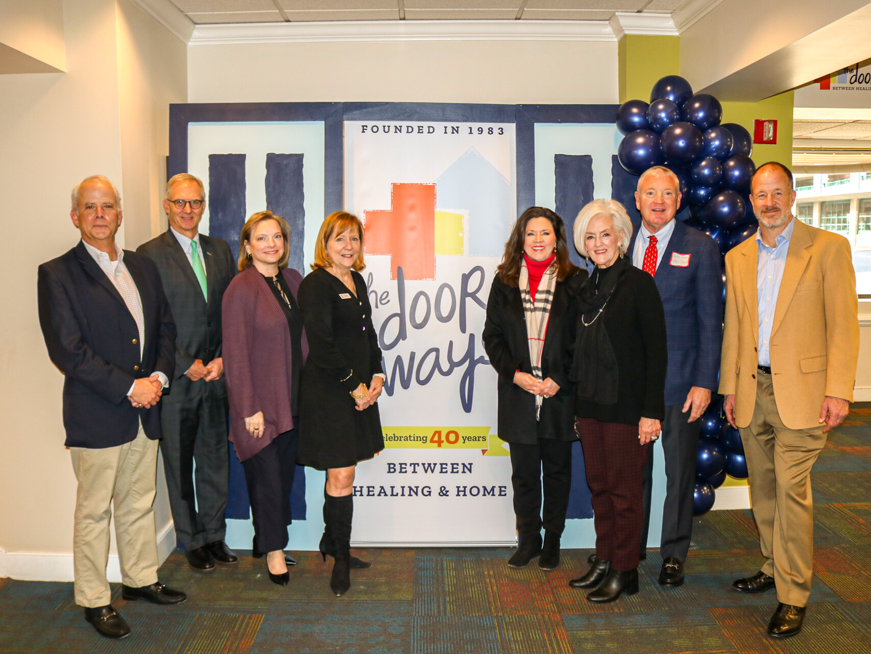 Group shot of multiple adults in front of a banner