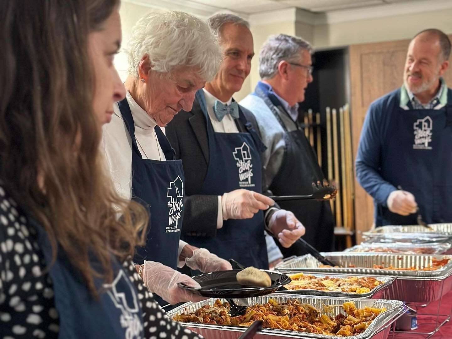 Group shot of multiple adults serving food
