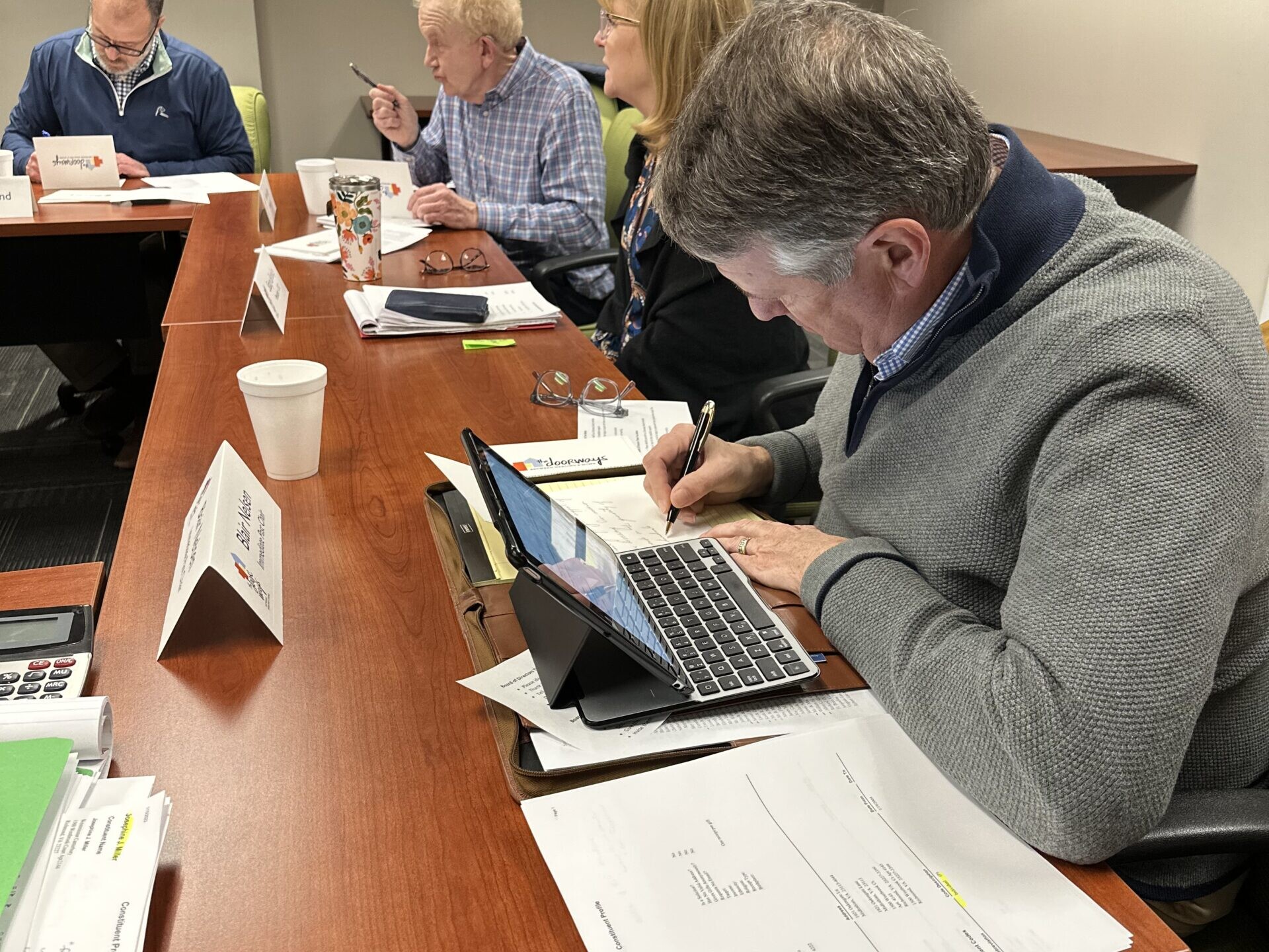 Group shot of multiple adults signing letters