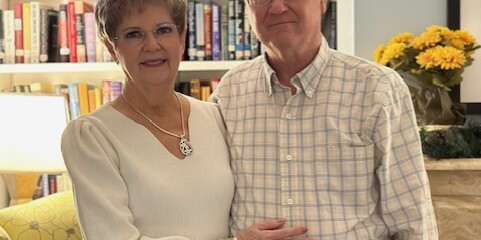 Two smiling adults stand in a library