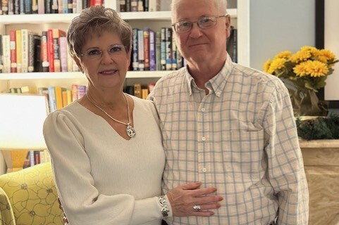 Two smiling adults stand in a library