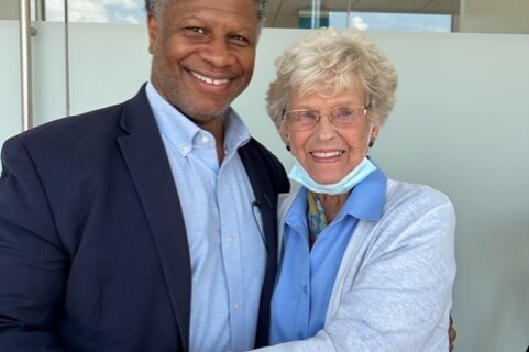 Two smiling adults hug each other