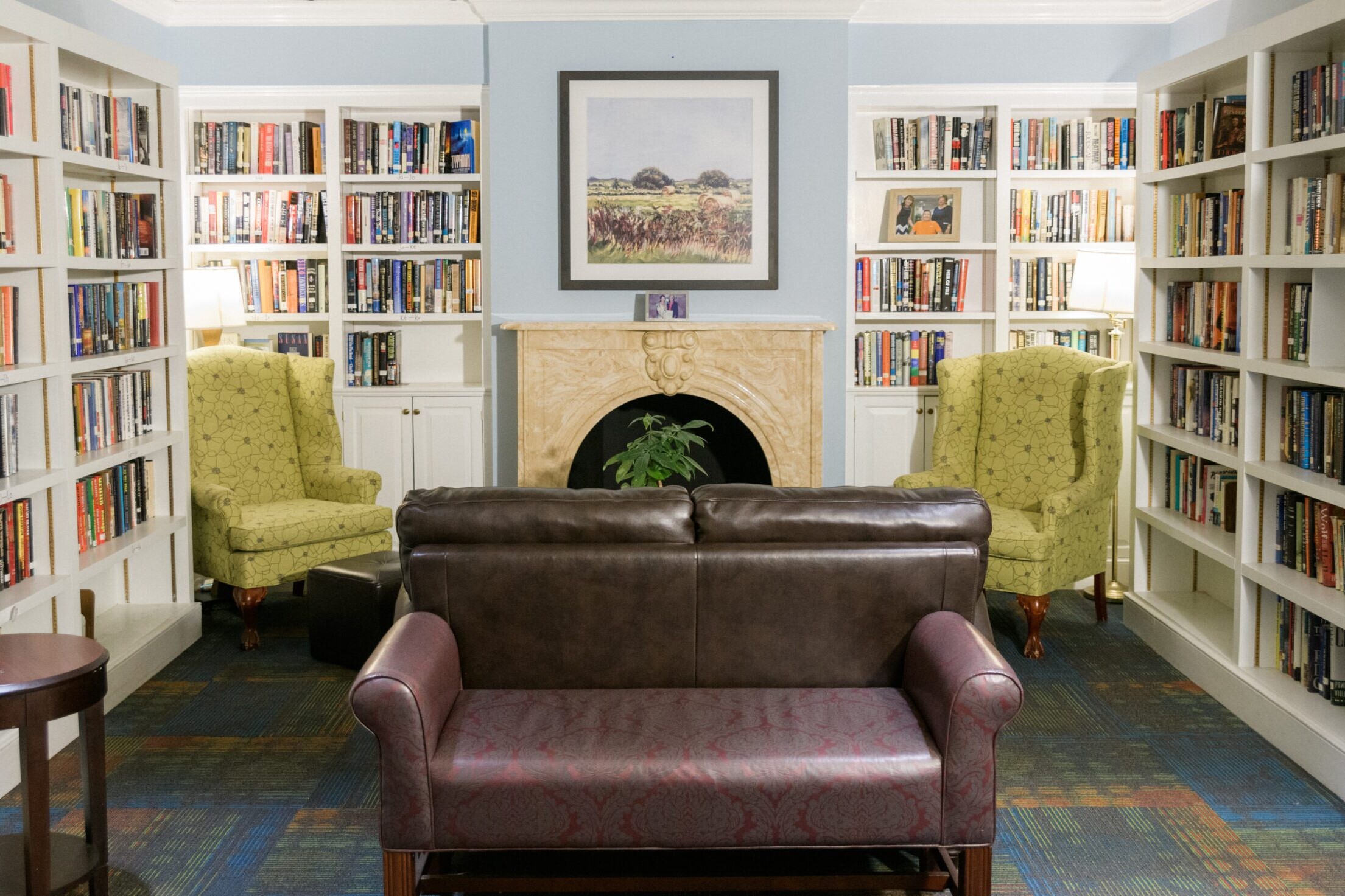 two couches and two chairs along with a fireplace are surrounded by books on bookshelves