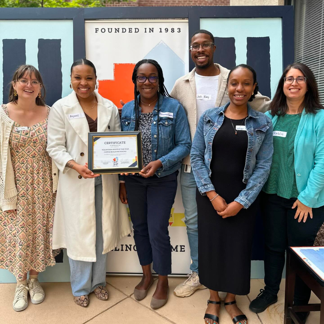 Six smiling adults hold up a volunteer appreciation award