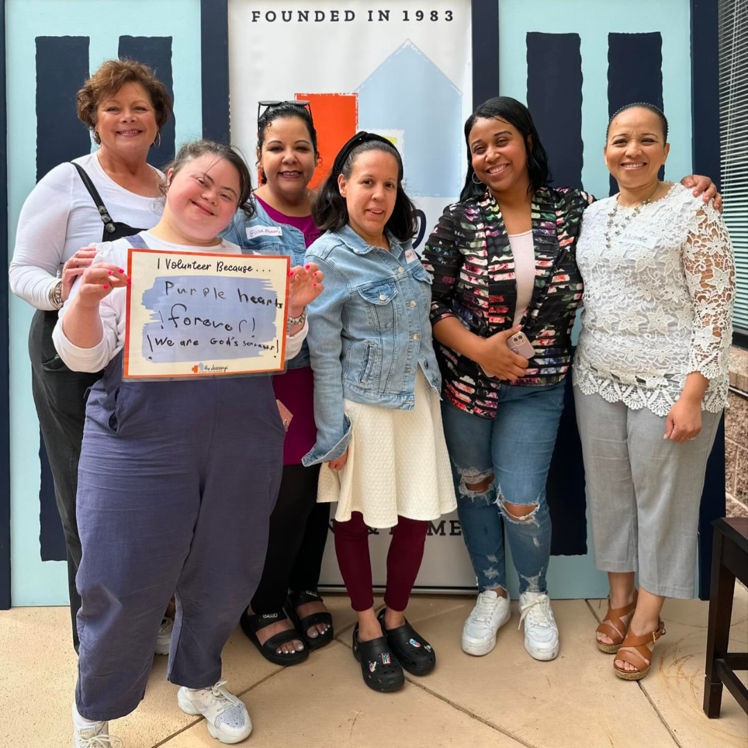 6 smiling people hold up a sign that reads 