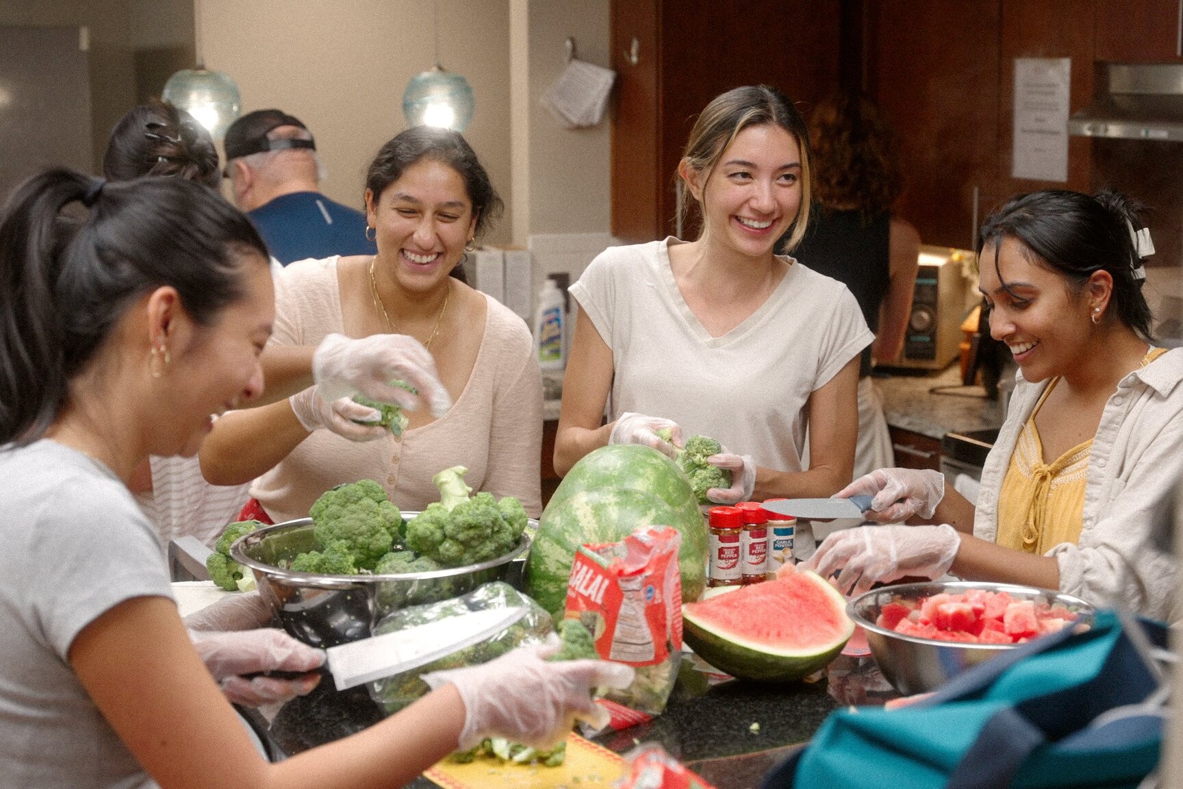 Several smiling young adults prepare a meal in the main kitchen of The Doorways