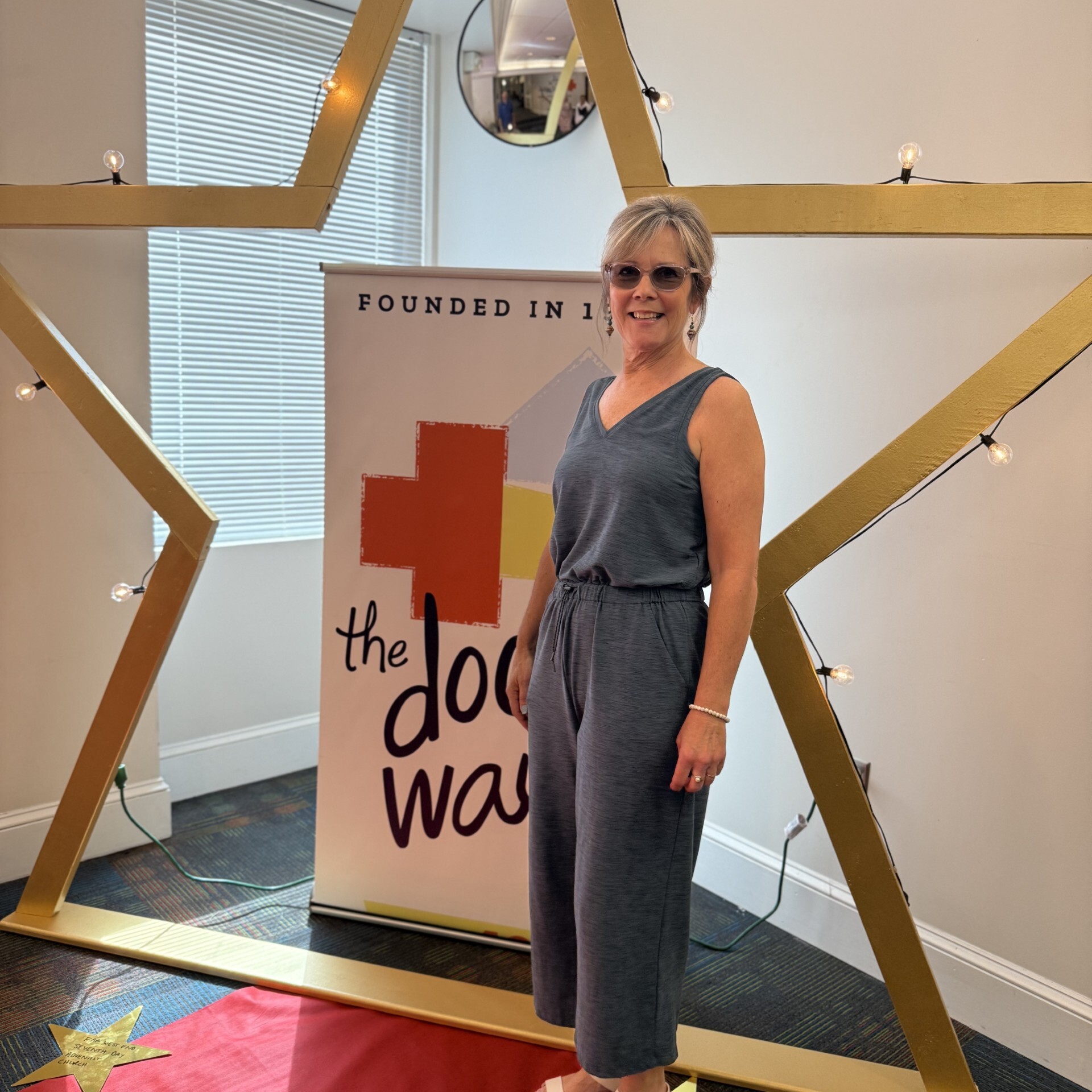A smiling staff member stands beside a star framing The Doorways banner