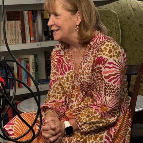 A smiling adult sits in a chair in the library of The Doorways