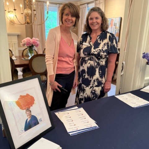 Two smiling staff members stand behind a registration table