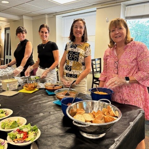 Four smiling staff members serve dinner to guests