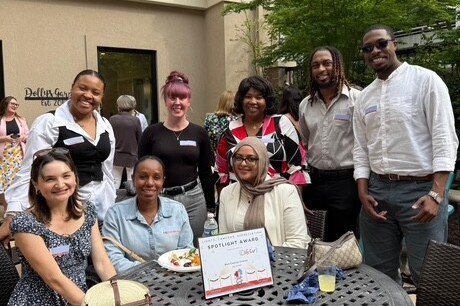 A smiling group of individuals pose with their volunteer appreciation award
