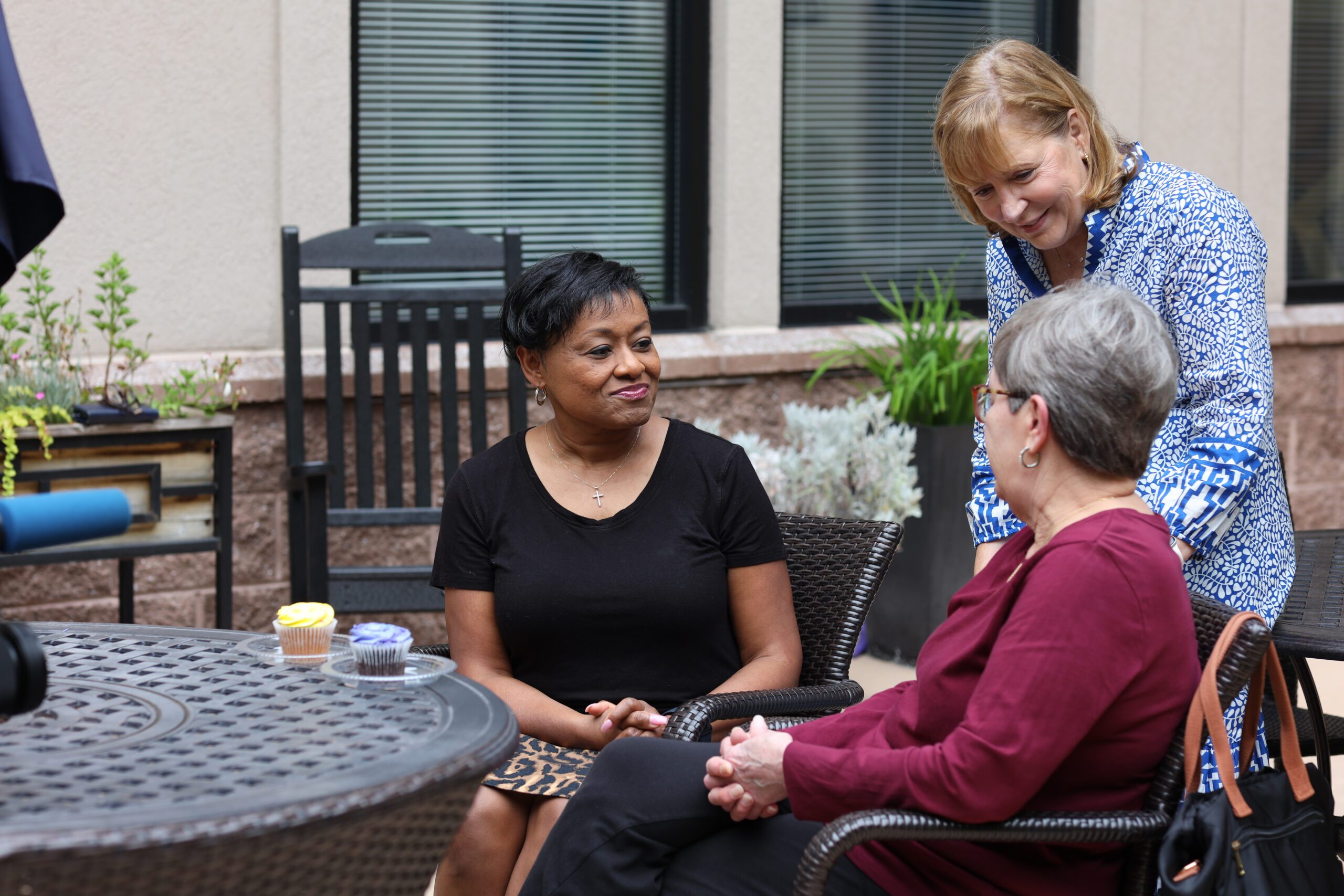 Three smiling people chat in Dolly's Garden at The Doorways