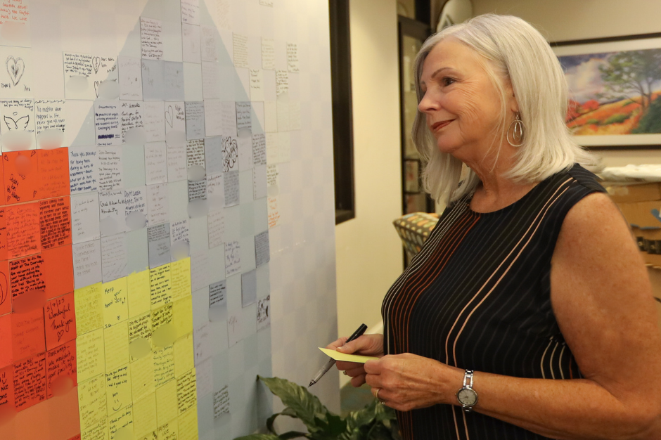 a smiling guest looks at the guest story wall in the lobby of The Doorways