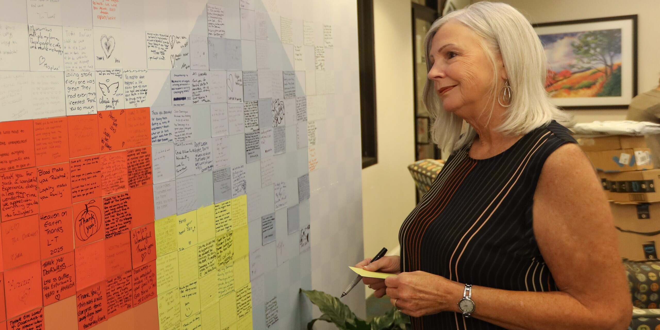 A smiling person looks at the guest story wall in the lobby of The Doorways