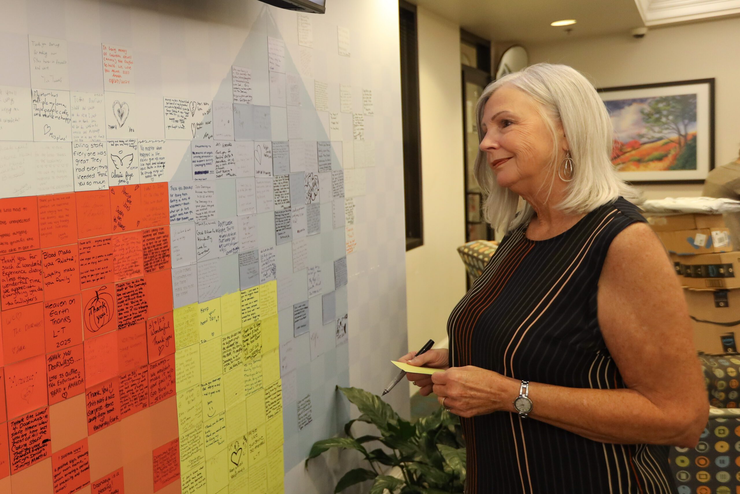A smiling person looks at the guest story wall in the lobby of The Doorways