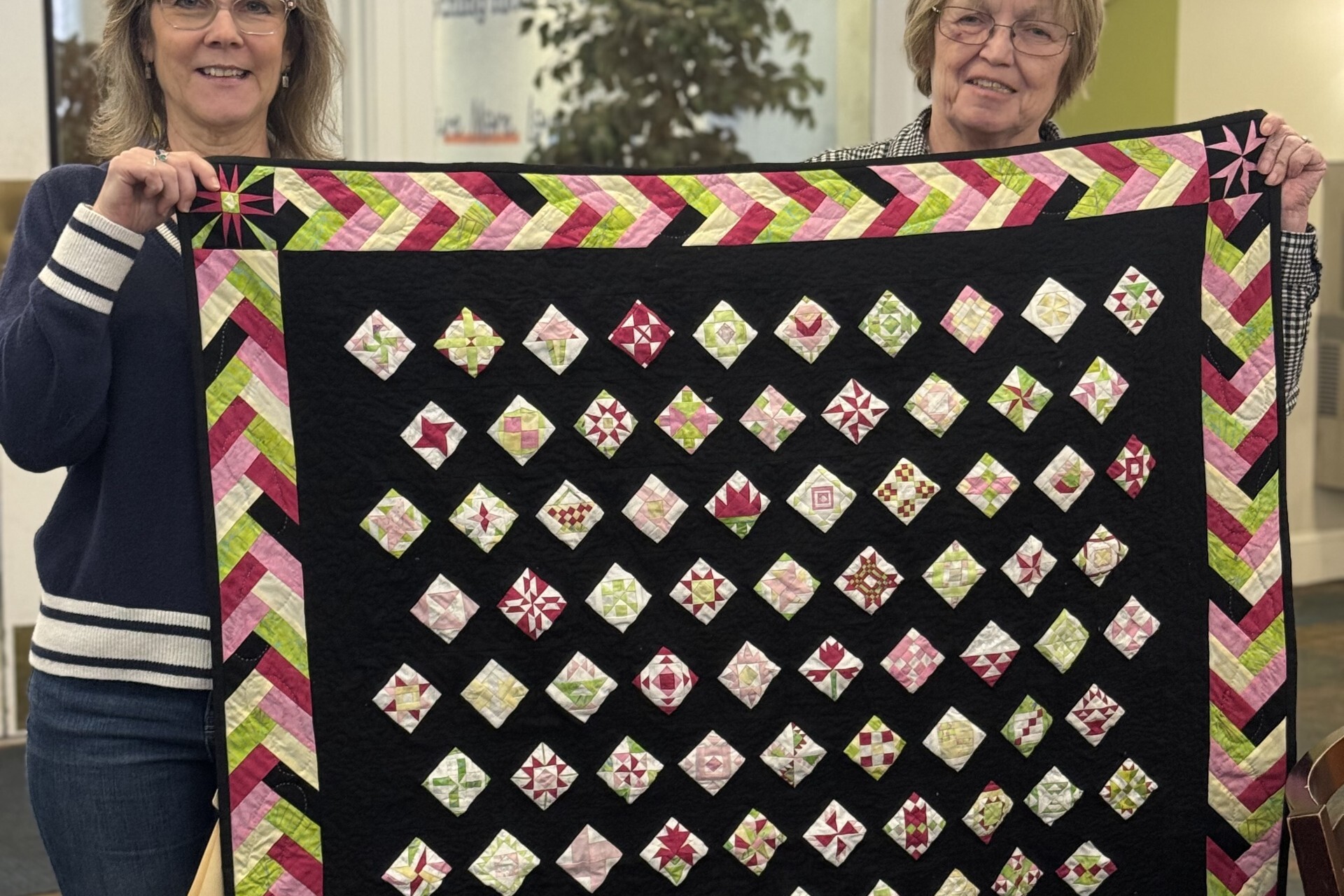 Guest and Volunteer Manager holding up quilt