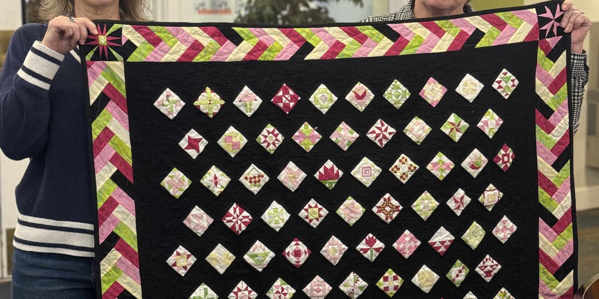 Guest and Volunteer Manager holding up quilt