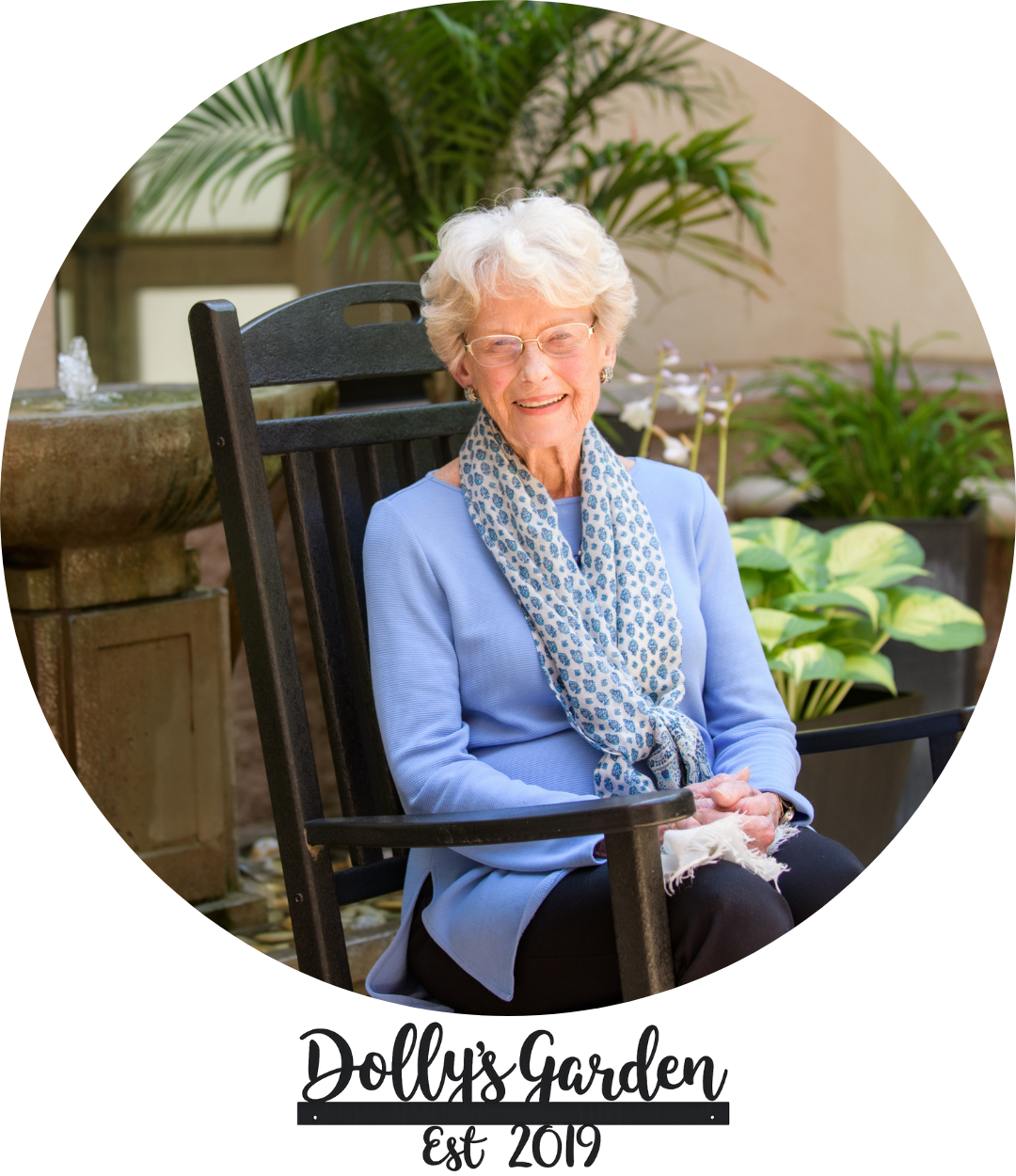 Dolly and sign a smiling adult in Dolly's Garden at The Doorways with a sign that reads "Dolly's Garden est. 2019"