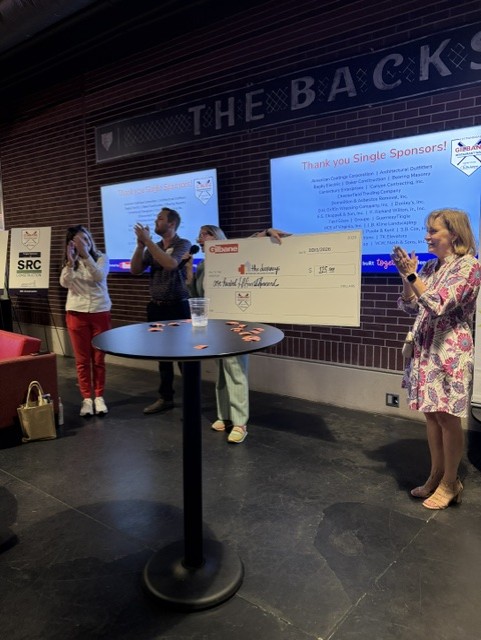 Smiling attendees at the 21st Annual Gilbane Restaurant Walk at CarMax Park with a giant check