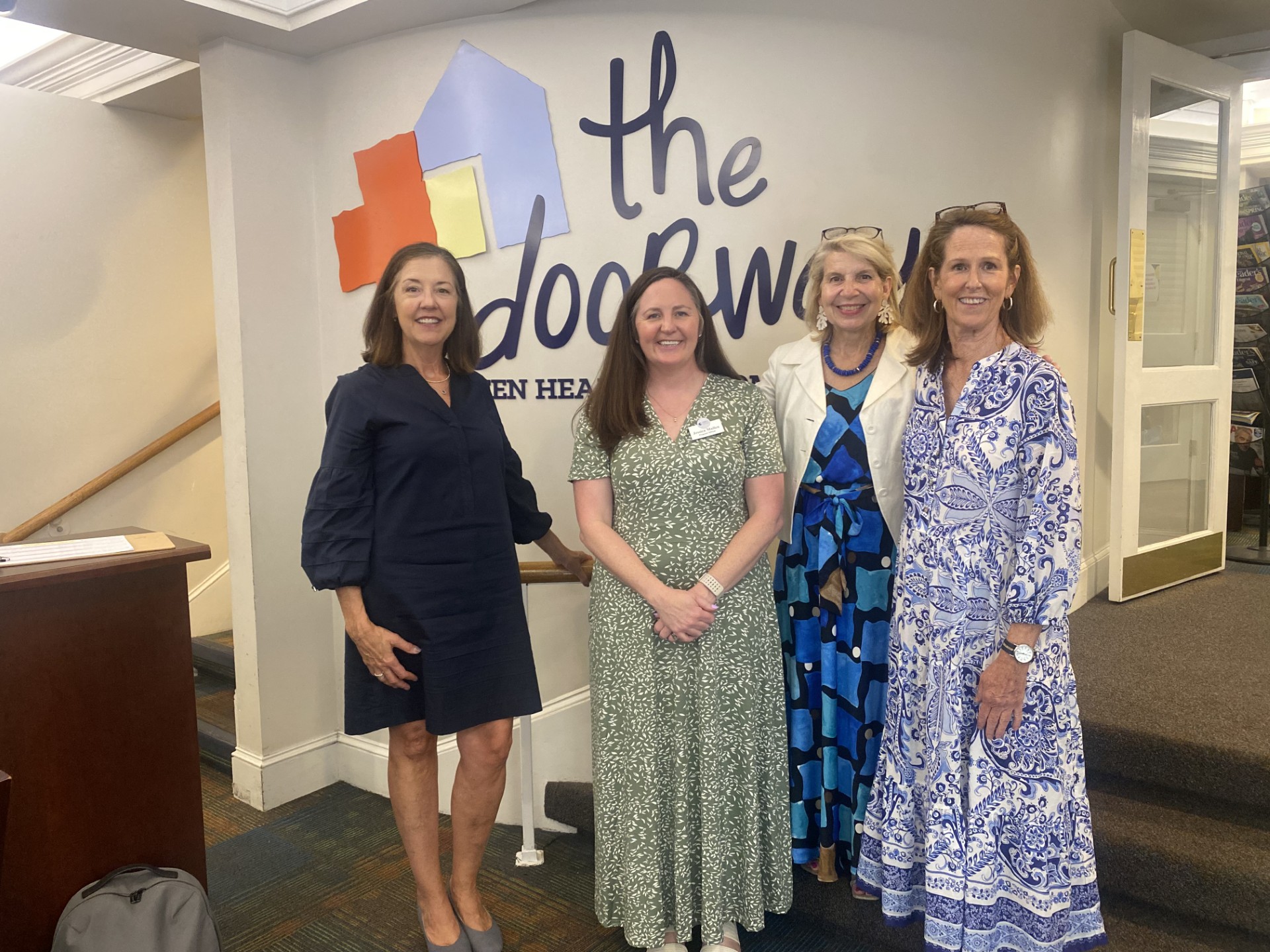 Obici Foundation Photo of 4 smiling adults standing in the lobby of The Doorways in front of The Doorways logo
