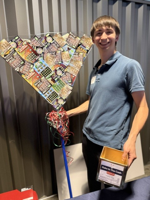 Smiling attendee poses with a rack filled with lottery tickets at the 21st Annual Gilbane Restaurant Walk at CarMax Park