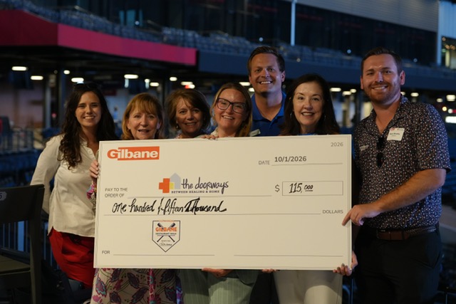 Smiling attendees at the 21st Annual Gilbane Restaurant Walk at CarMax Park with a giant check