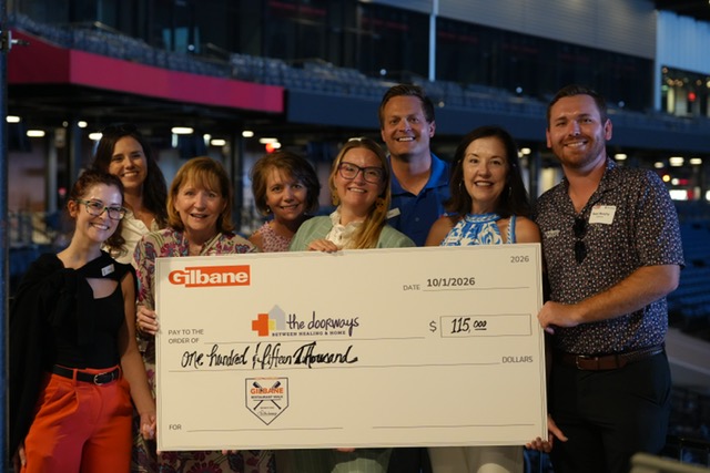 Smiling attendees at the 21st Annual Gilbane Restaurant Walk at CarMax Park with a giant check