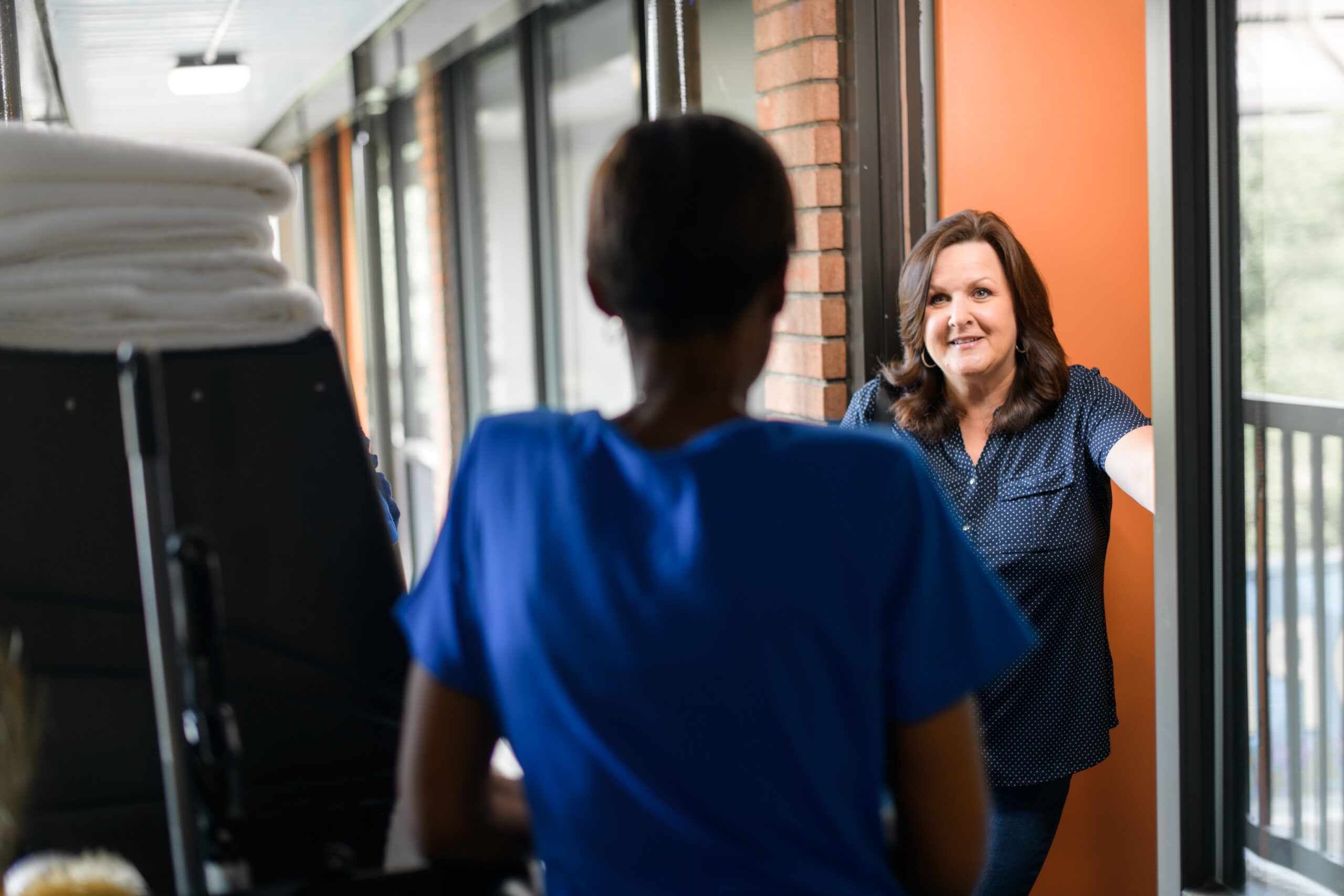 a smiling guest interacts with a housekeeper in a doorframe of a guest room