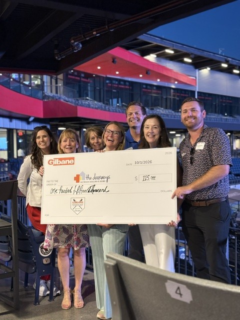 Smiling attendees at the 21st Annual Gilbane Restaurant Walk at CarMax Park with a giant check