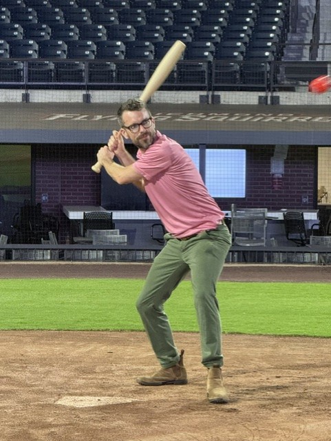 Smiling attendee playing wiffleball at the 21st Annual Gilbane Restaurant Walk at CarMax Park
