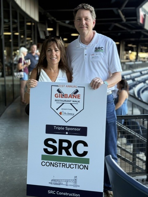 Smiling attendees at the 21st Annual Gilbane Restaurant Walk at CarMax Park with SRC sponsorboard